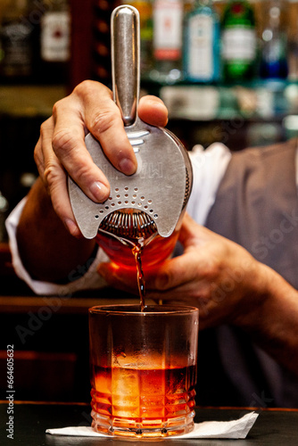 Barman pouring negroni on glass close up