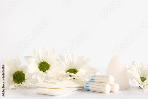 Female hygiene items and chamomile flowers on light background
