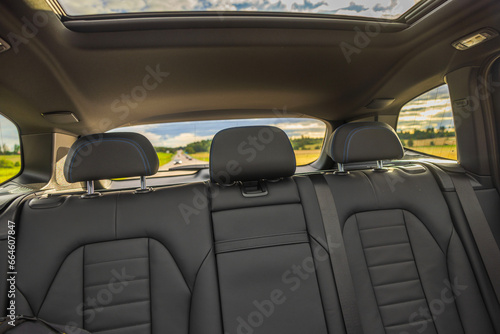 Beautiful rear view interior with leather seats and panoramic sunroof of new black electric car driving on highway. Sweden. © Alex