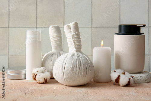 Composition with spa accessories, cosmetic products and cotton flowers on table against light tile background