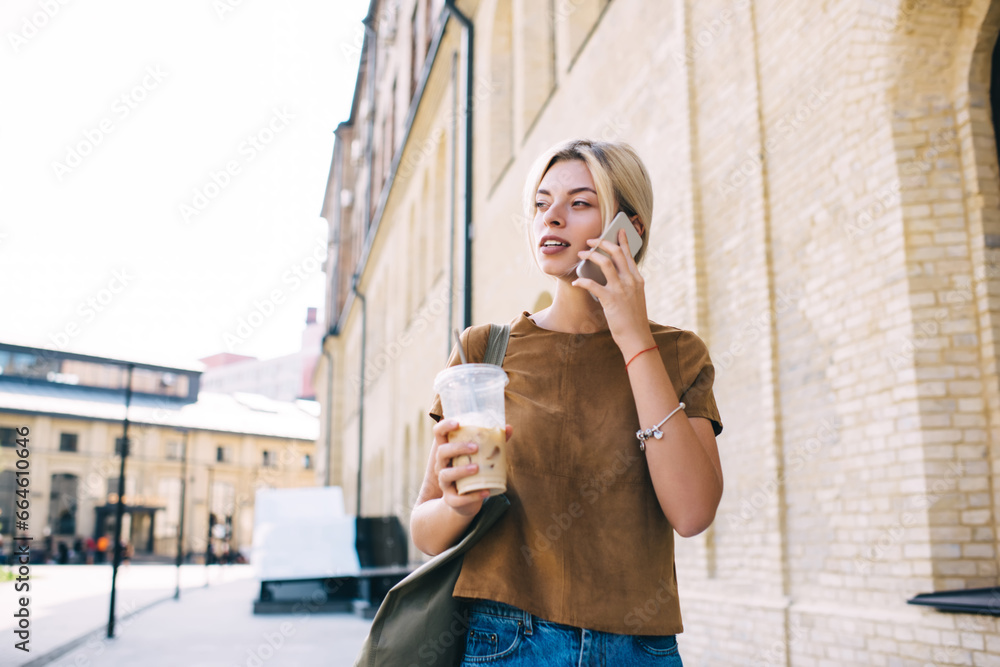 Φωτογραφία Millennial female tourist with ice coffee to go making international phone conve