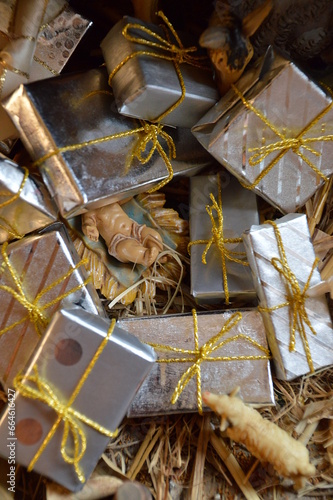 Jesus the baby in the manger hidden under a pile of presents as critical symbol for our excessive consuming society that forgot the  literal meaning of Christmas