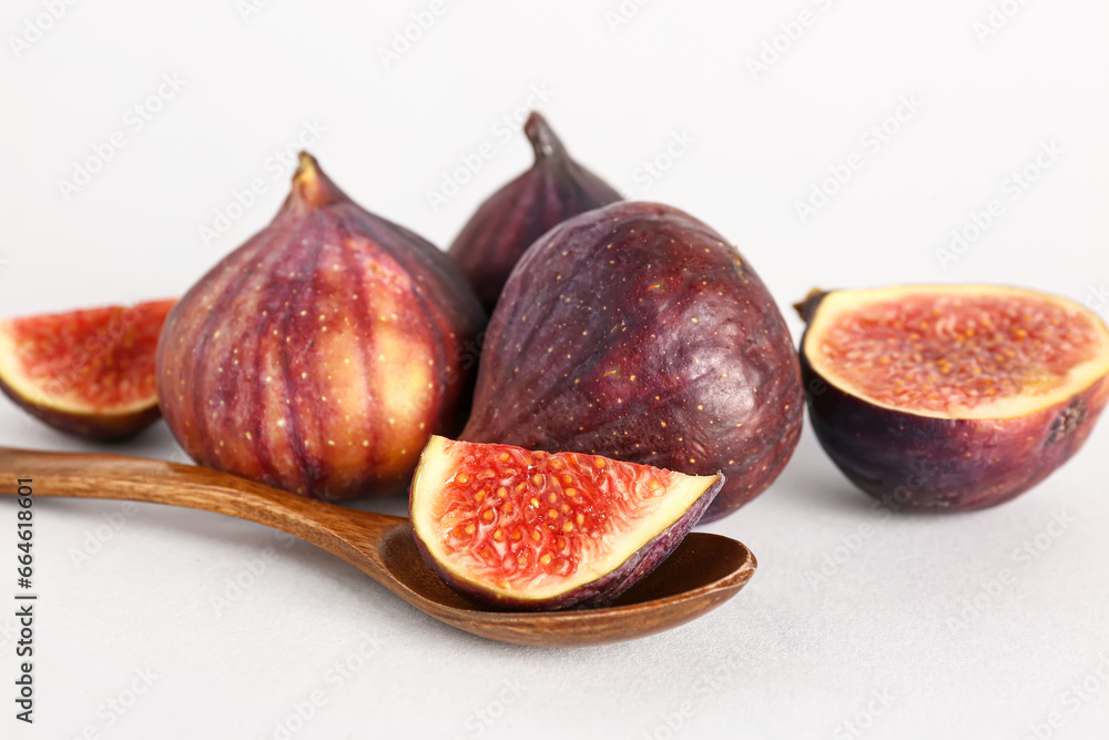 Fresh ripe figs and wooden spoon with piece on white background Fresh ripe figs and wooden spoon with piece on white background