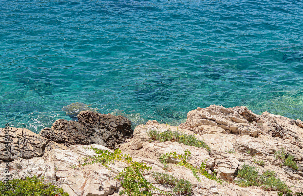 Rocky shore and turquoise calm sea water on sunny summer day Rocky shore and turquoise calm sea water on sunny summer day