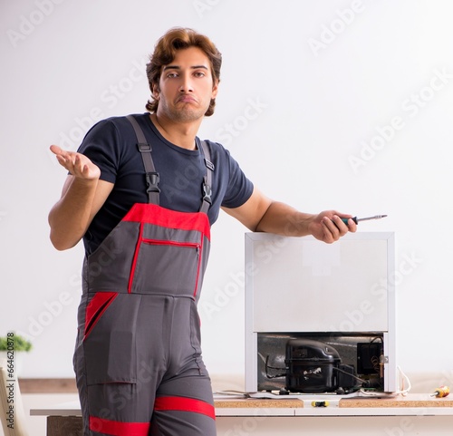 Fotografie Young handsome contractor repairing fridge