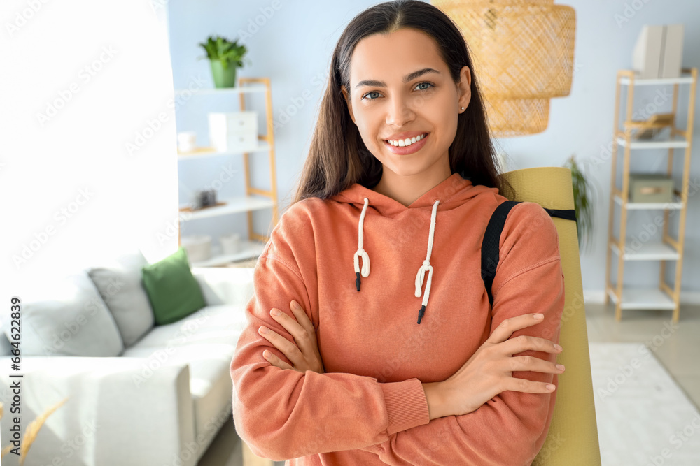 Young woman in hoodie with fitness mat at home Young woman in hoodie with fitness mat at home