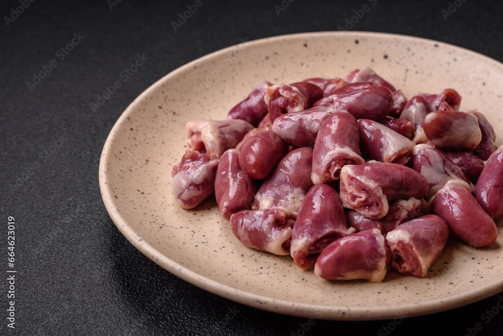 Fresh raw chicken, turkey or duck hearts on a ceramic plate with salt and spices Fresh raw chicken, turkey or duck hearts on a ceramic plate with salt and spices