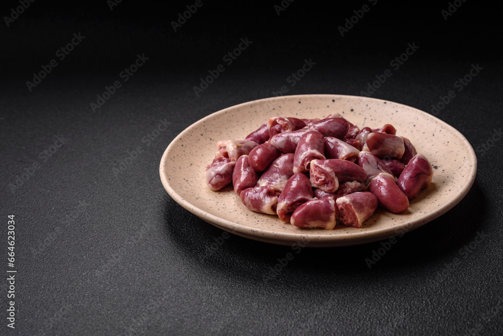 Fresh raw chicken, turkey or duck hearts on a ceramic plate with salt and spices Fresh raw chicken, turkey or duck hearts on a ceramic plate with salt and spices