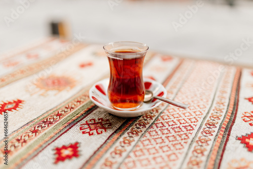 Turkish black tea in national dishes stands on the table with a napkin with Turkish patterns. Dessert close-up. Breakfast in a cafe. Turkish ornament photo