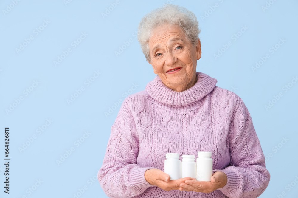 Senior woman with pill bottles on blue background Senior woman with pill bottles on blue background