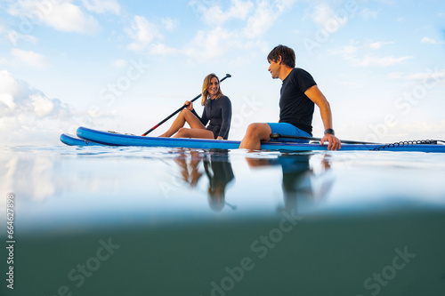 Young man and woman on the sea with a paddle surf board photo