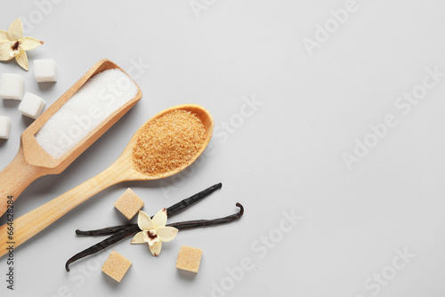 Wooden scoop and spoon with aromatic vanilla sugar on grey background