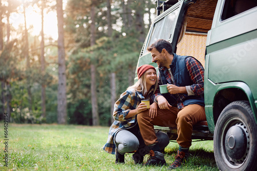 Happy couple enjoys in cup of warm tea while camping in nature in autumn. photo