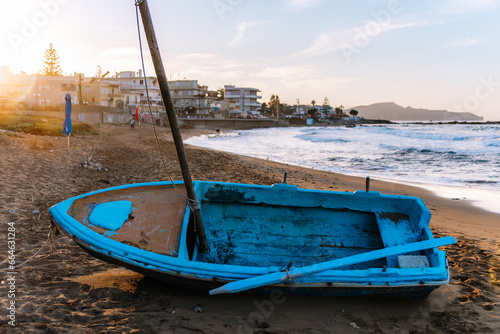 traditional Greek fishing boat on the shore at sunset on Crete, Greece.