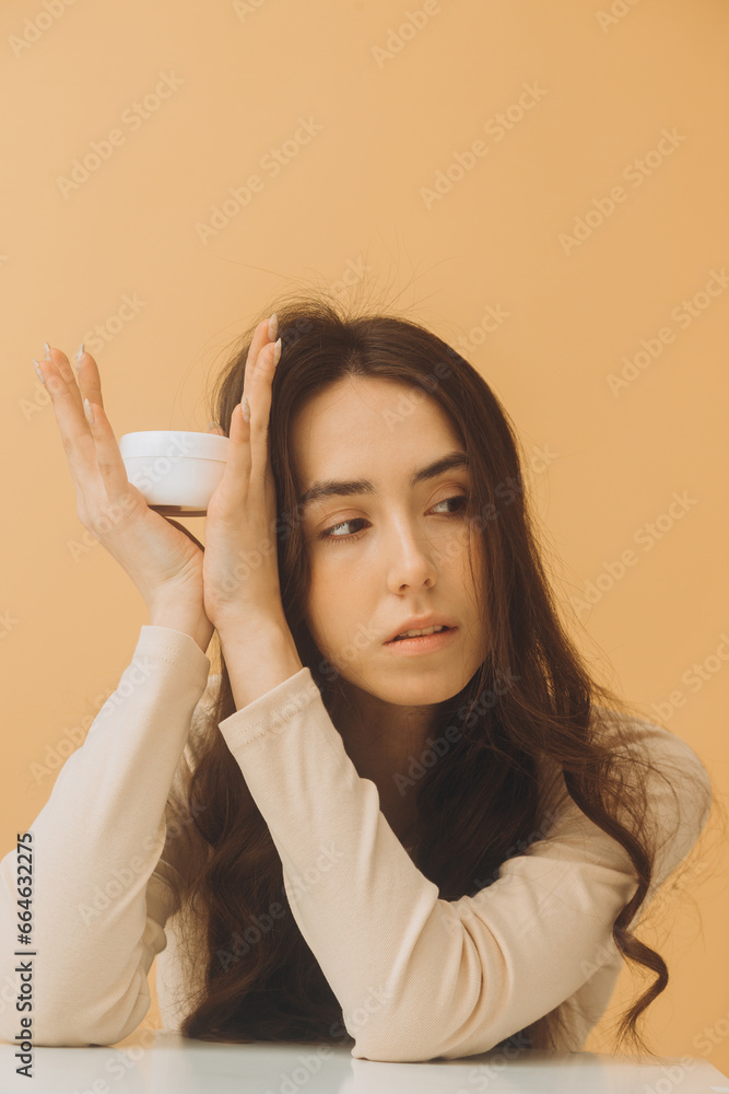 Beautiful woman with jar of moisturizer cream. Photo of woman with perfect skin on beige background. Beauty and Skin care concept. Beautiful woman with jar of moisturizer cream. Photo of woman with perfect skin on beige background. Beauty and Skin care concept.