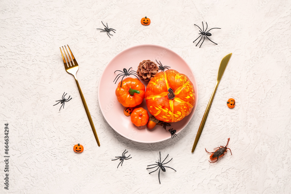 Halloween table setting with pumpkins and spiders on white grunge background Halloween table setting with pumpkins and spiders on white grunge background