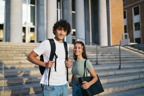 Portrait of cheerful college students with casual clothes smiling and looking at camera while standing outdoors at the university