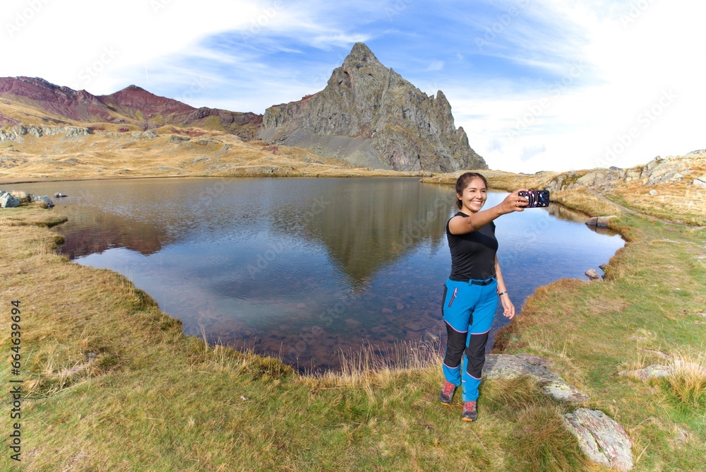 Naklejka premium Latin girl taking a selfie in a mountain lake. in the French Pyrenees