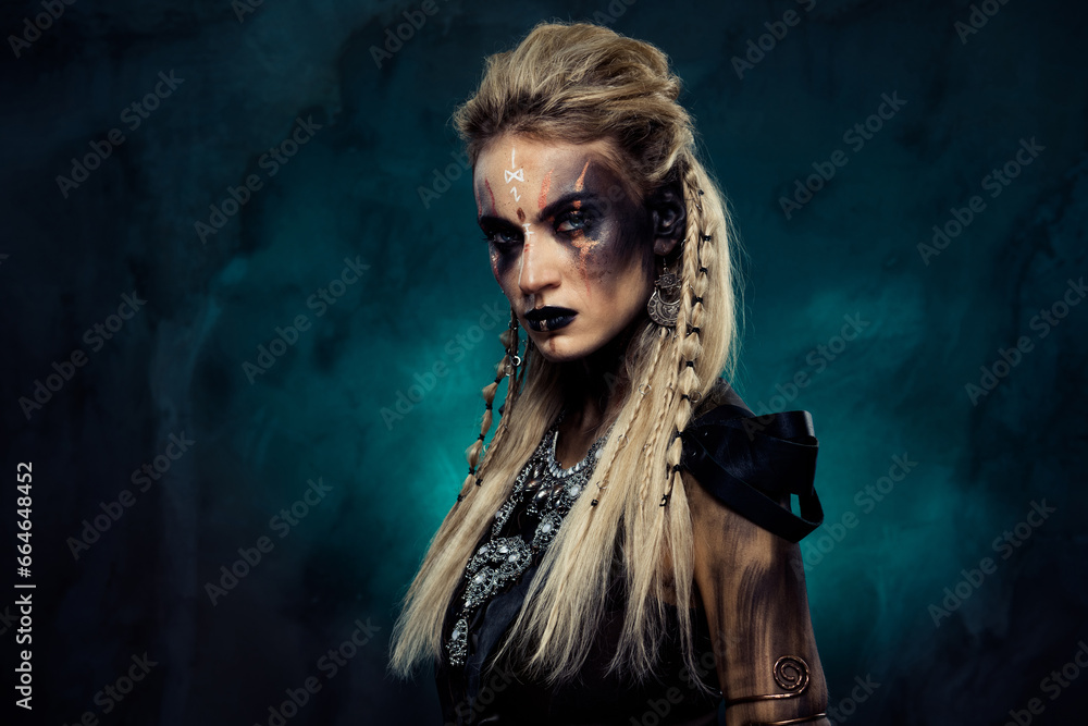 Photo of dangerous powerful shield maiden tribal queen demonic viking ready for fierce war over dark mist background - obrazy, fototapety, plakaty 