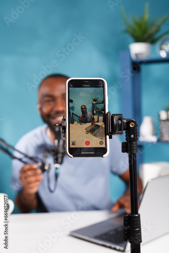 Canvas Print Smiling blogger on smartphone screen live streaming on social media channel