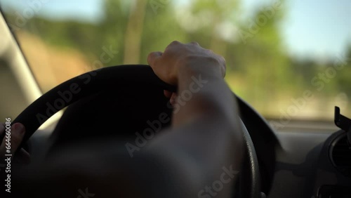 Man driving a car, hands on steering wheel with background of the road