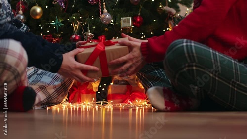 family couple exchange gifts box sitting under decorated Christmas tree baubles balls and blinking golden lights garland. tradition boxing day next morning after Christmas night concept