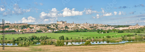 panoramic aerial image of the east side of the old town of Toledo with green fields and the Tagus River in the foreground