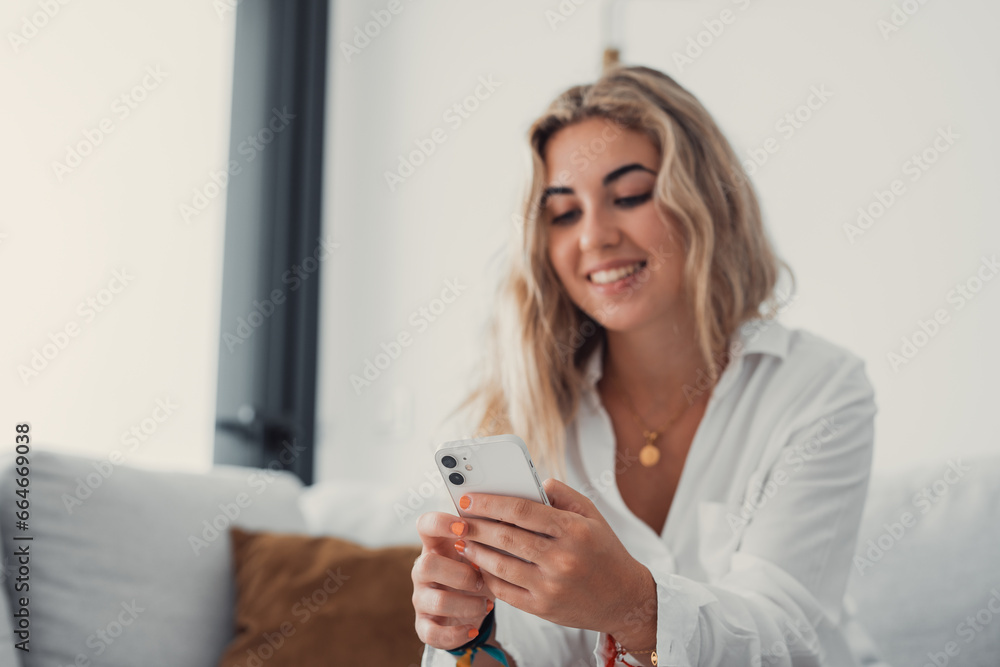 Portrait of one young attractive blonde woman using phone cell on couch relaxing surfing the net at home. Relaxing online concept lifestyle. Portrait of one young attractive blonde woman using phone cell on couch relaxing surfing the net at home. Relaxing online concept lifestyle.