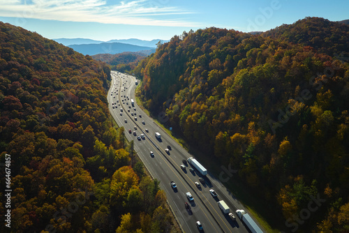 View from above of I-40 freeway in North Carolina heading to Asheville through Appalachian mountains in golden fall season with fast driving trucks and cars. Interstate transportation concept photo