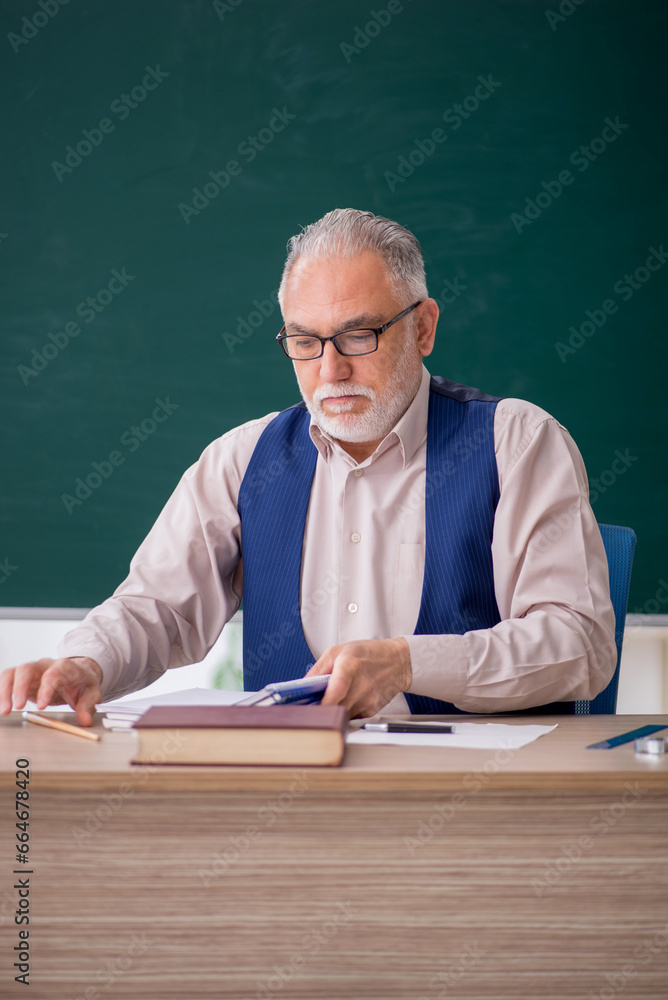 Old male teacher in front of green board Old male teacher in front of green board