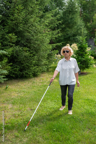 Elderly blind woman walking in the park. 