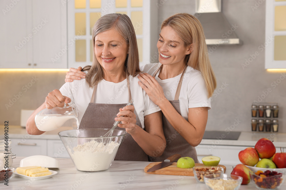 Happy mature mother and her daughter cooking together at kitchen Happy mature mother and her daughter cooking together at kitchen