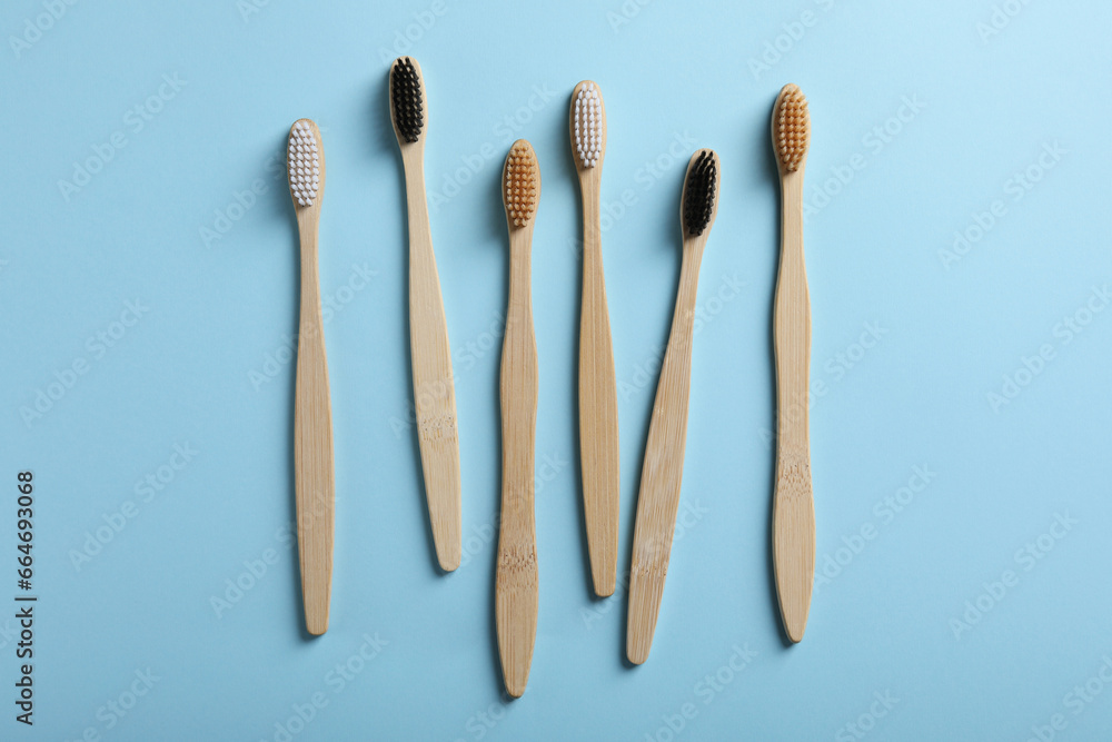Bamboo toothbrushes on light blue background, flat lay