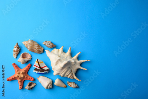 Beautiful starfish, decorative ship and shells on blue background, flat lay. Space for text
