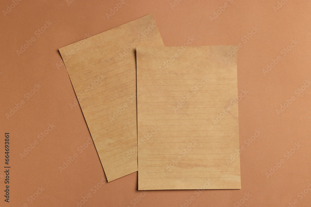Fototapeta premium Sheets of old parchment paper on brown background, flat lay