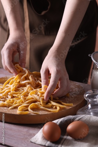 Woman making homemade pasta at wooden table, closeup