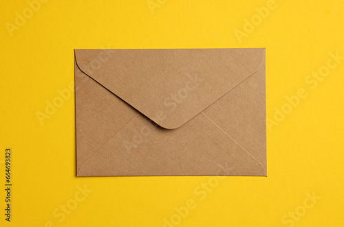 Envelope made of parchment paper on yellow background, top view