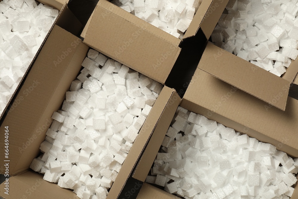 Open cardboard boxes with pieces of polystyrene foam on floor, flat lay. Packaging goods - obrazy, fototapety, plakaty 