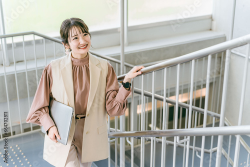 オフィスの階段を登る女性・ビジネスウーマン（朝・出社・通勤） 