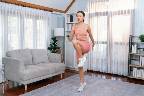 Energetic and strong athletic asian woman running in place at her home. Pursuit of fit physique and commitment to healthy lifestyle with home workout and training. Vigorous