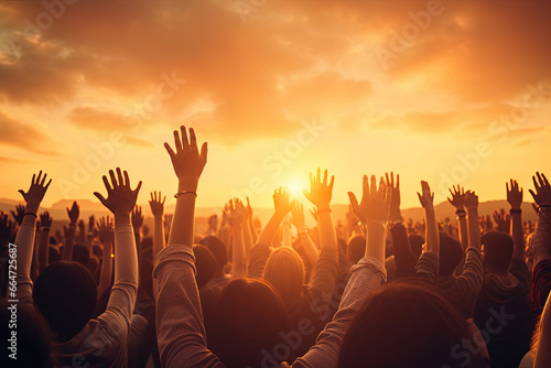 Worship and praise concept  Christian people raising their hands in a unified crowd at sunset