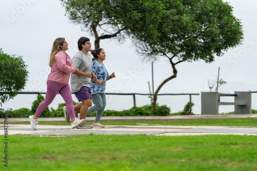 Side view of three fat people running along a path