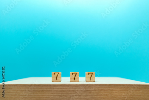 木目の台の上に7が3つ揃ったラッキーを連想させる青い背景