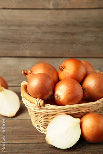 Fresh healthy onions and sliced onion on basket on grey wooden background. Vertical photo