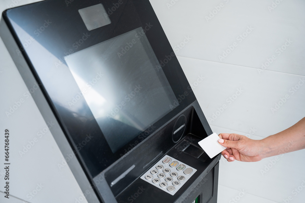 A faceless woman inserts a credit card into an ATM. Close-up of a woman's hands using an ATM machine. A faceless woman inserts a credit card into an ATM. Close-up of a woman's hands using an ATM machine.