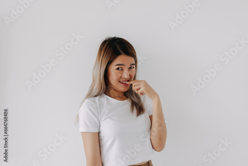 Happy asian Thai woman smiling look at camera, biting finger, shy and embarrassing, isolated on white background.