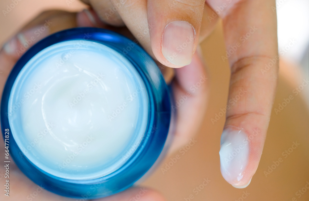 Hand of woman holding moisturizer cream and serum. She applying a facial cream , essential , oil , lotion and body cream for skin care, close up view and blur background. Beauty and Healthy Concept. Hand of woman holding moisturizer cream and serum. She applying a facial cream , essential , oil , lotion and body cream for skin care, close up view and blur background. Beauty and Healthy Concept.