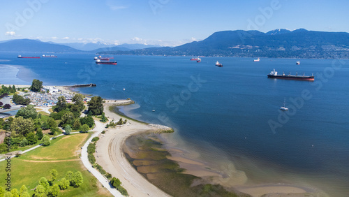 Aerial view of Burrard Inlet from Jericho Beach. Cargo ships sit in the water. West Vancouver in the background