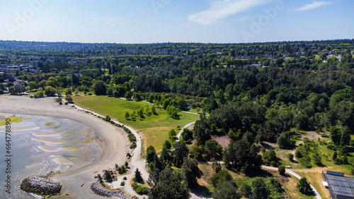 Jericho Beach on a sunny morning. Sandy beach wrapped around by forest and in between neatly cut grass. View of kitsalano and point grey in the distance 