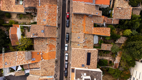 Above a small street in Montpellier, France. Red tiled roofs faded from the sun. Cars line the narrow street. 
